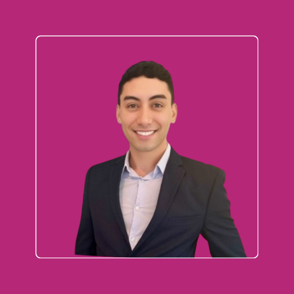 Wilfredo, career reinvention coaching client, smiling headshot on a magenta background